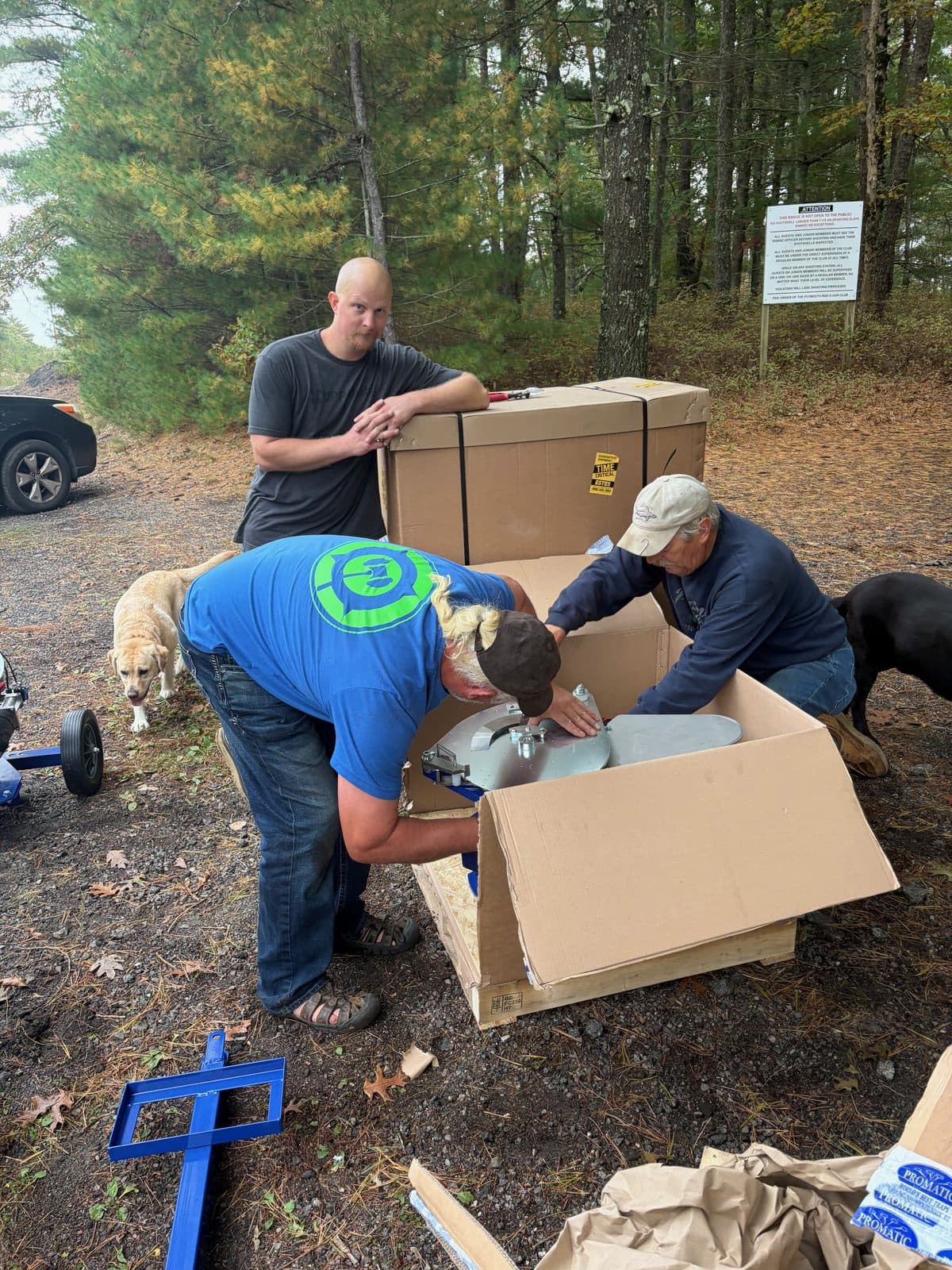 Members unboxing a sporting clays thrower from its crate