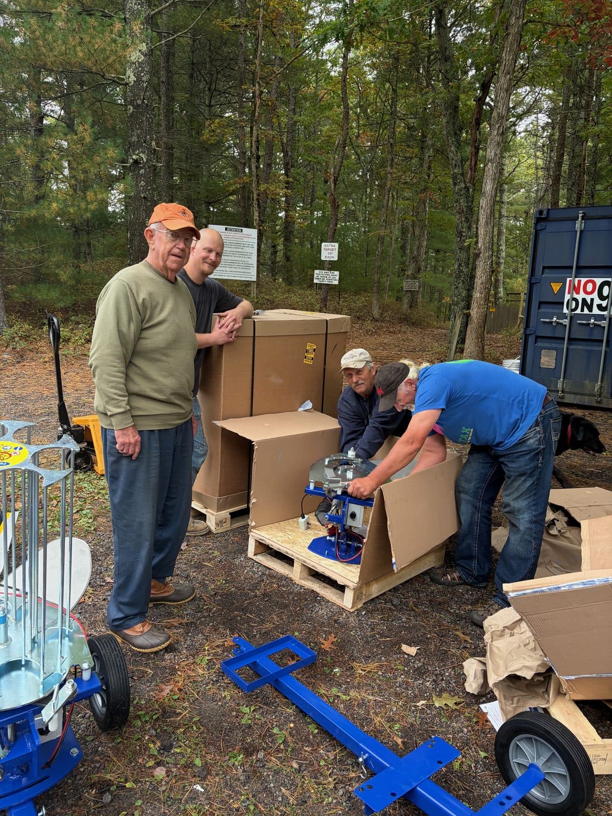 Four members unboxing new sporting clays machines